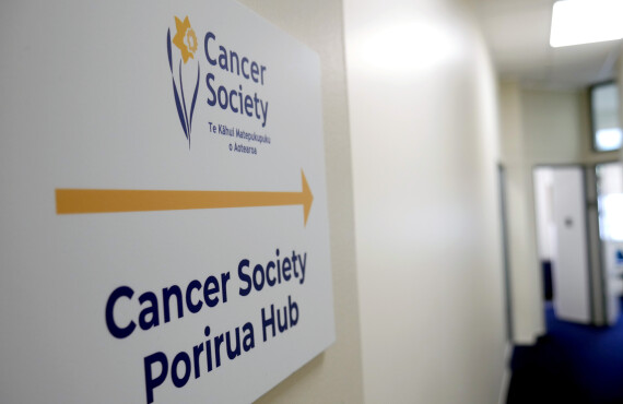 Cancer Society Porirua Hub sign with office in background.